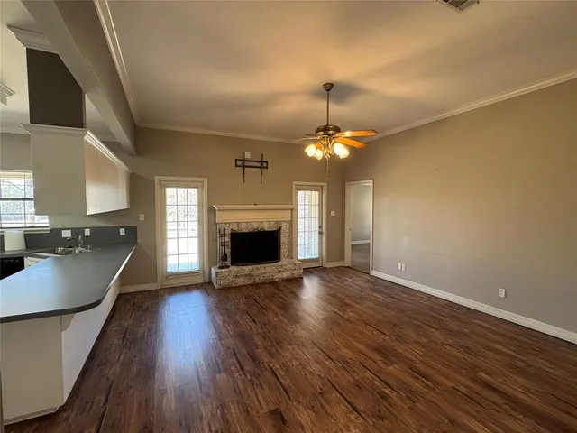 a view of an empty room with wooden floor and a fireplace