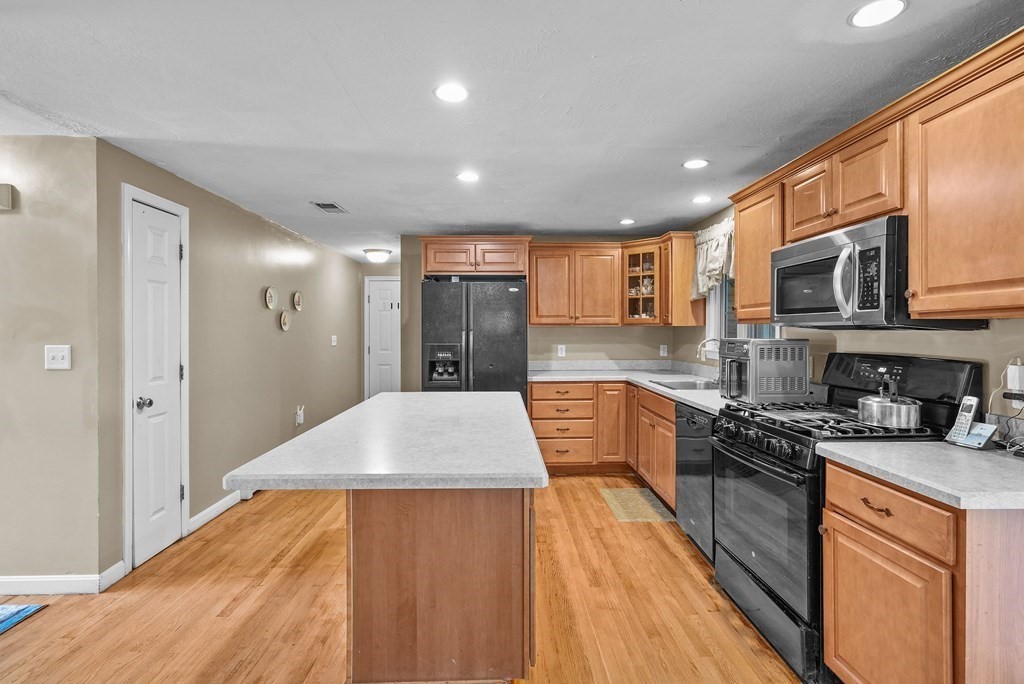 2 Commons Drive Carver, MA 02330 - Photo 6 of 37 a kitchen with stainless steel appliances granite countertop a refrigerator a stove top oven a sink dishwasher and white cabinets with wooden floor