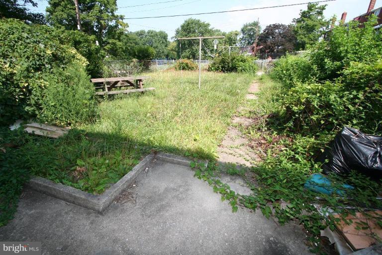 5010 West Hills Road Baltimore, MD 21229 - Photo 3 of 30 a view of a backyard with plants and a bench with wooden fence