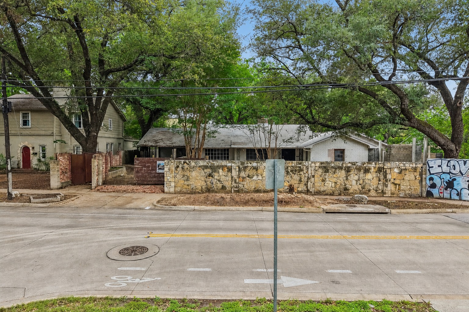 801 East 32nd Street Austin, TX 78705 - Photo 1 of 13 Mature trees canopy this property, featuring a stone fence along the street.