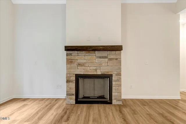 a view of an empty room with wooden floor and a fireplace