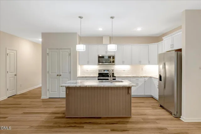a kitchen with kitchen island stainless steel appliances a stove refrigerator and a sink