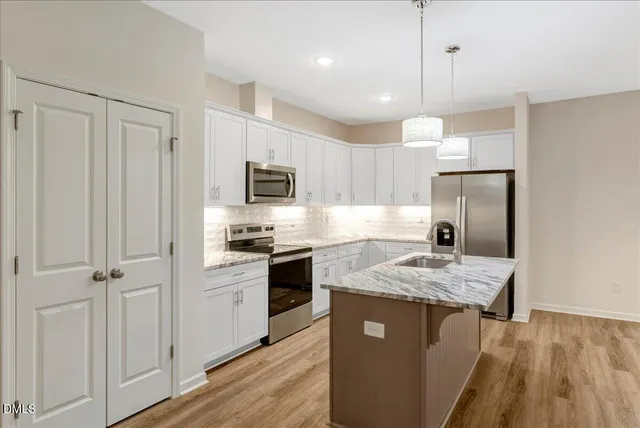 a kitchen with kitchen island granite countertop a sink stainless steel appliances and white cabinets