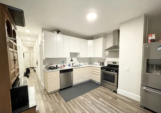 a kitchen with stainless steel appliances granite countertop a stove top oven a refrigerator a sink and dishwasher with wooden floor