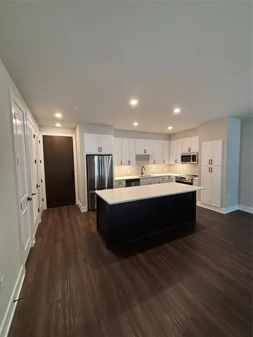 a large kitchen with stainless steel appliances kitchen island a large counter top and wooden floors