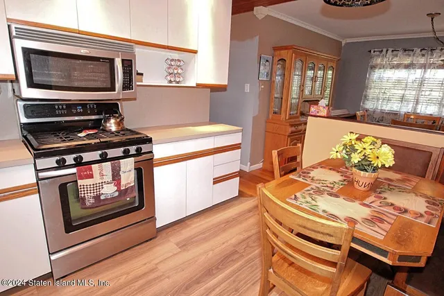 a kitchen with stainless steel appliances wooden floor dining table and chairs
