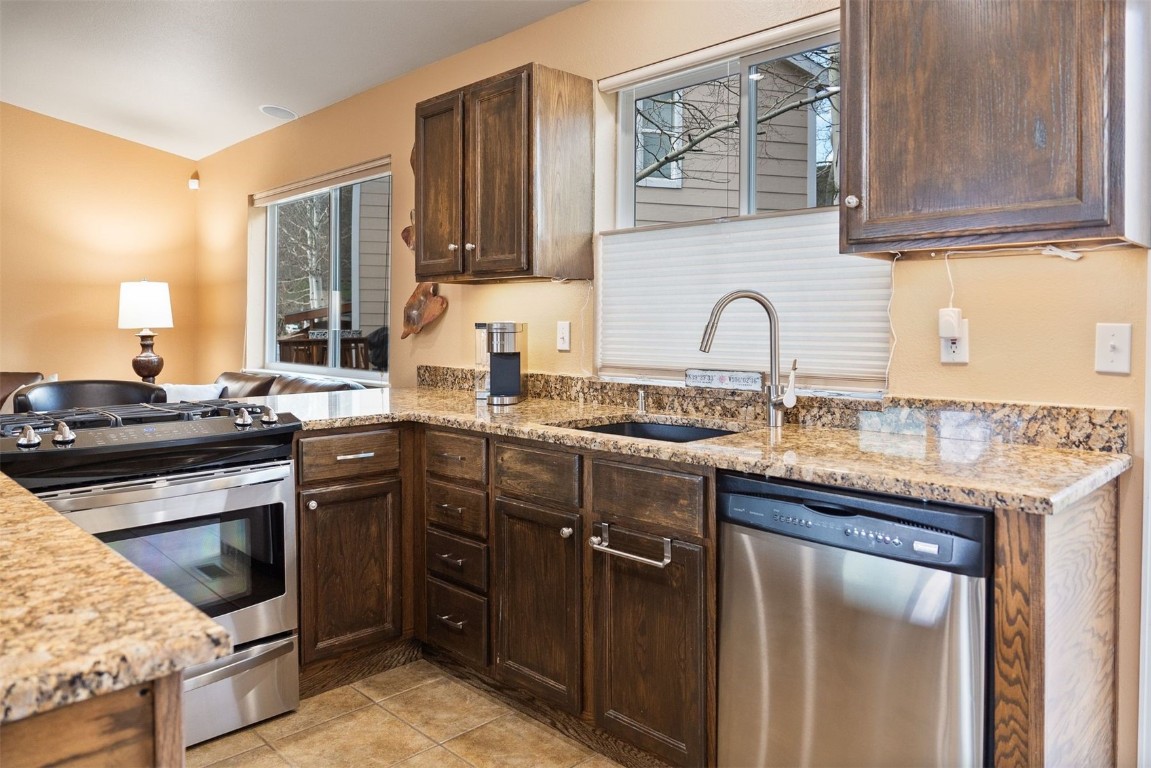 588 Alpine Road Dillon, CO 80435 - Photo 4 of 41 Kitchen featuring dark brown cabinets, stainless steel appliances, light stone counters, light tile floors, and sink