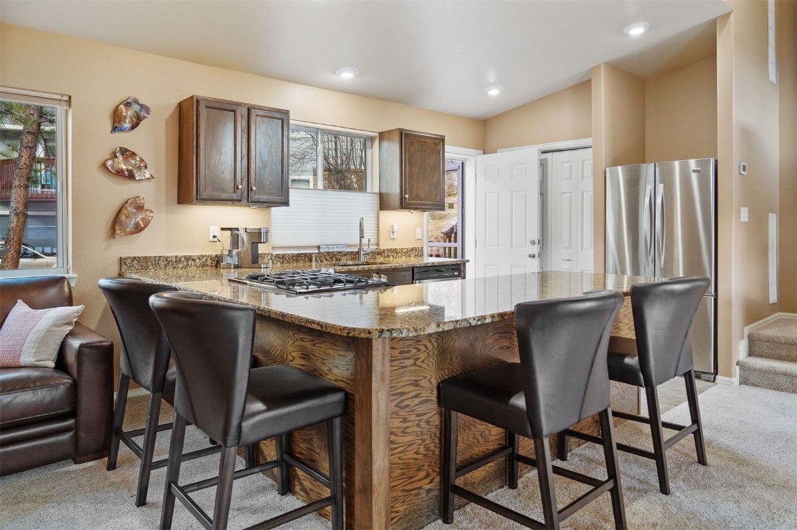 588 Alpine Road Dillon, CO 80435 - Photo 6 of 41 Kitchen with light granite countertops, lofted ceiling, kitchen peninsula, a breakfast bar, and light colored carpet