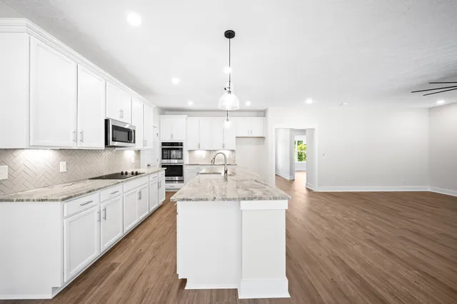 a large kitchen with stainless steel appliances kitchen island granite countertop a sink and cabinets