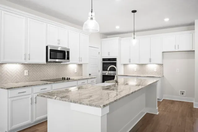 a kitchen with stainless steel appliances granite countertop a sink a stove and a microwave