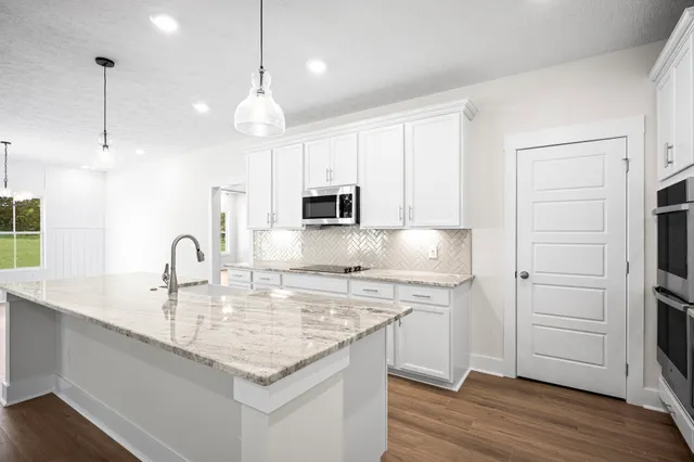 a kitchen with stainless steel appliances granite countertop a sink a stove and a wooden floors