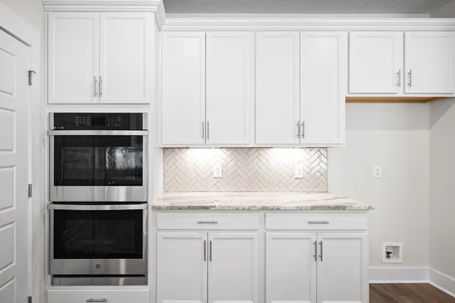 a kitchen with granite countertop white cabinets and stainless steel appliances