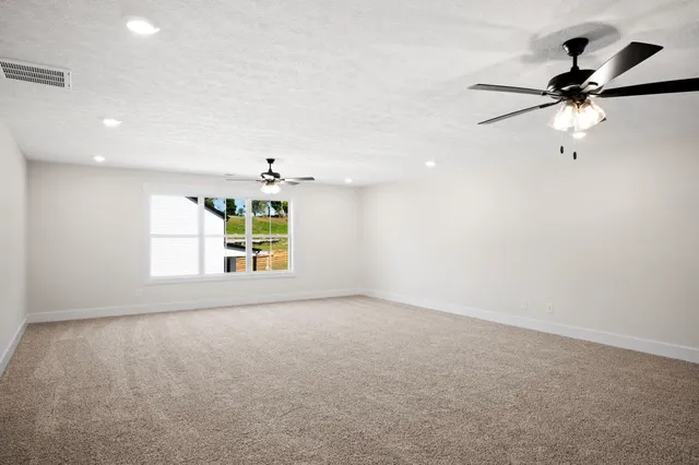 an empty room with a ceiling fan and a window