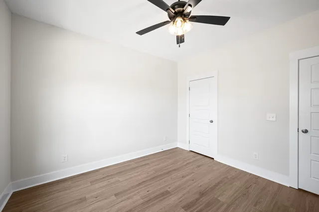 an empty room with wooden floor and a ceiling fan
