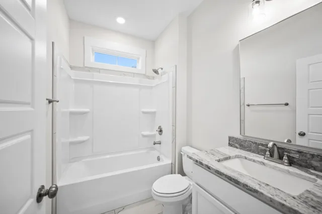 a bathroom with a granite countertop toilet a sink and a bathtub