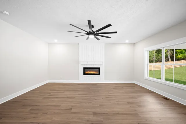 a view of an empty room with a window and wooden floor