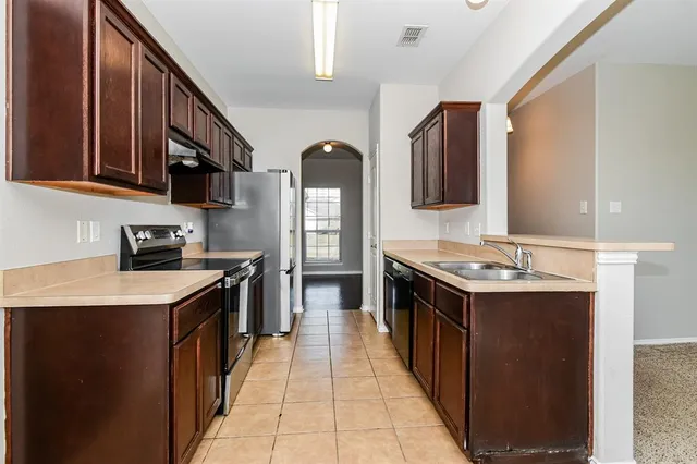 a kitchen with stainless steel appliances granite countertop a stove top oven a sink a counter space and cabinets