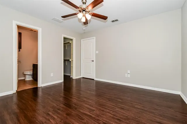 an empty room with wooden floor closet and windows
