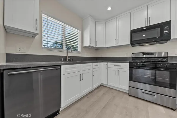 a kitchen with stainless steel appliances granite countertop a sink a stove a microwave and cabinets