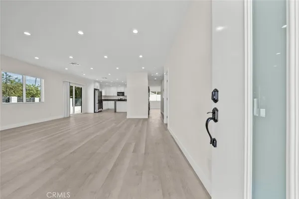 a view of a hallway with wooden floor and a bathroom
