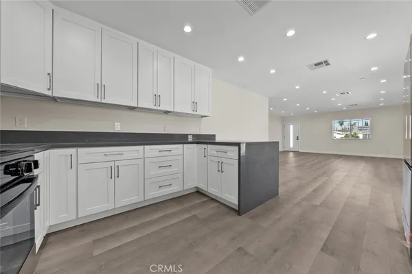 a open white kitchen with cabinets and wooden floor