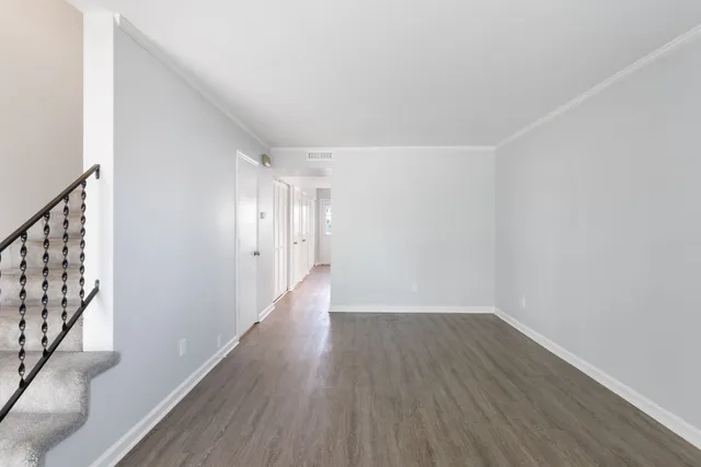a view of an empty room with wooden floor and stairs