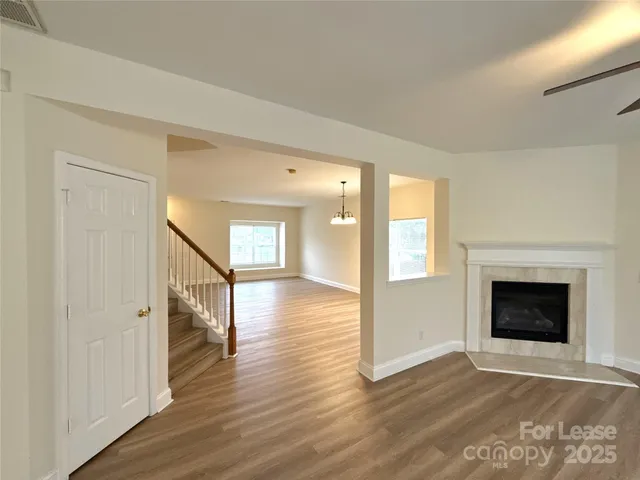 a view of an empty room with wooden floor fireplace and a window