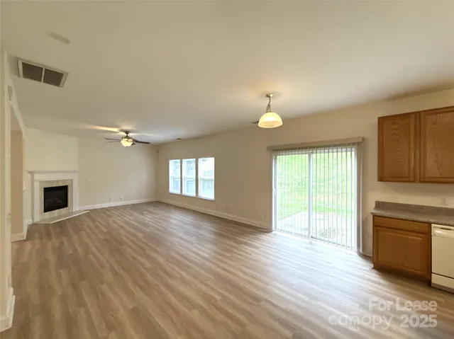 an empty room with wooden floor fireplace and windows