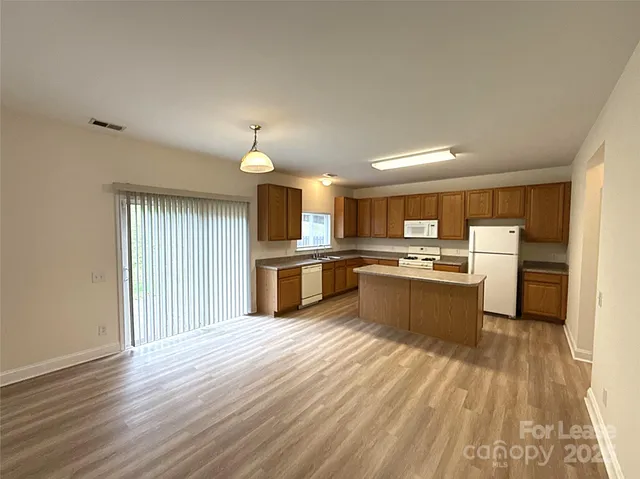 a large kitchen with kitchen island a sink wooden floor and stainless steel appliances