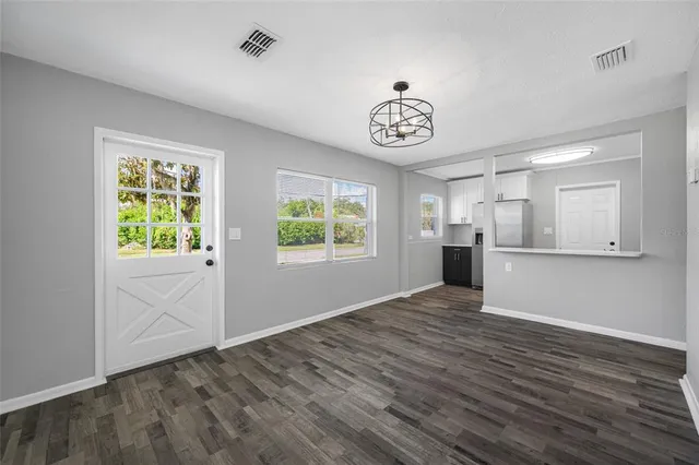 a view of an empty room with a window and wooden floor