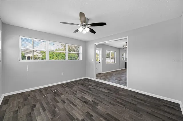 a view of empty room with wooden floor and fan