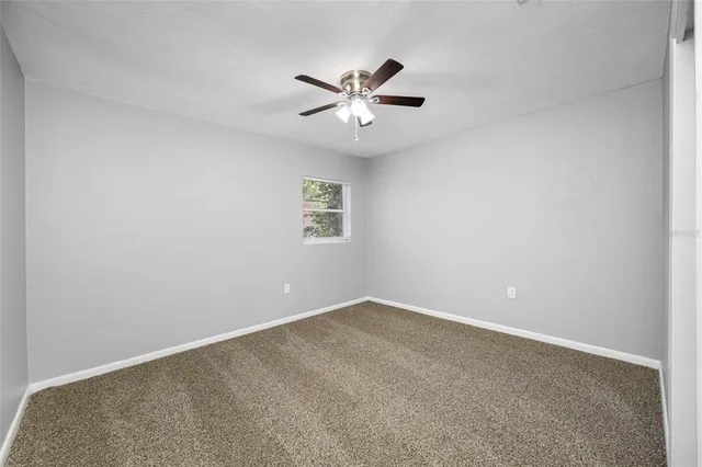 an empty room with a window and a fan