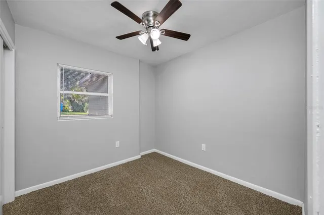an empty room with a window and a fan