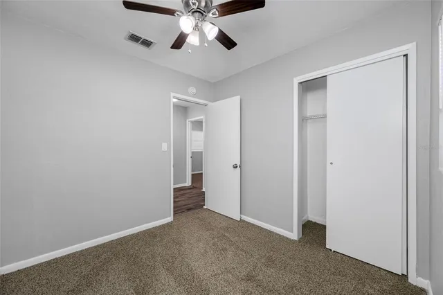 a view of an empty room and chandelier fan
