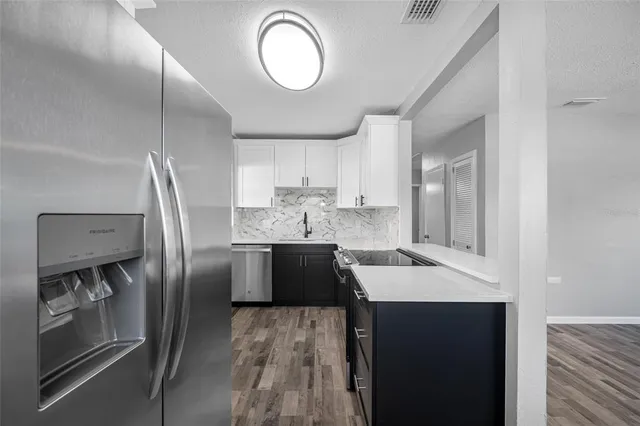 a kitchen with stainless steel appliances granite countertop a sink refrigerator and cabinets