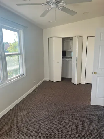 a view of empty room with window and ceiling fan