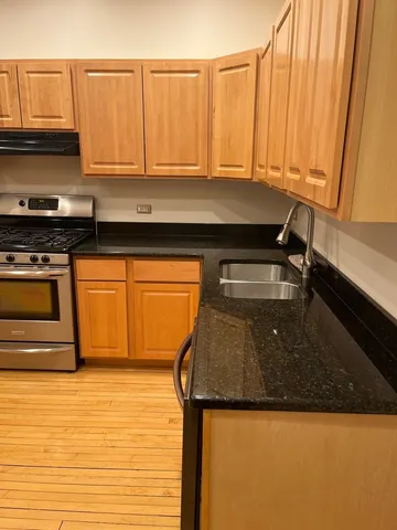 a kitchen with granite countertop a sink a stove and cabinets