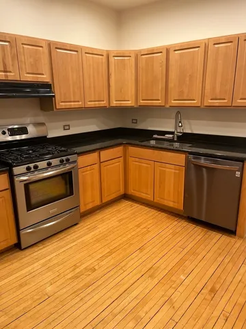 a kitchen with granite countertop wooden cabinets stainless steel appliances and a sink