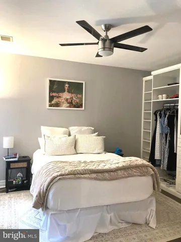 a bedroom with a bed painting and a ceiling fan