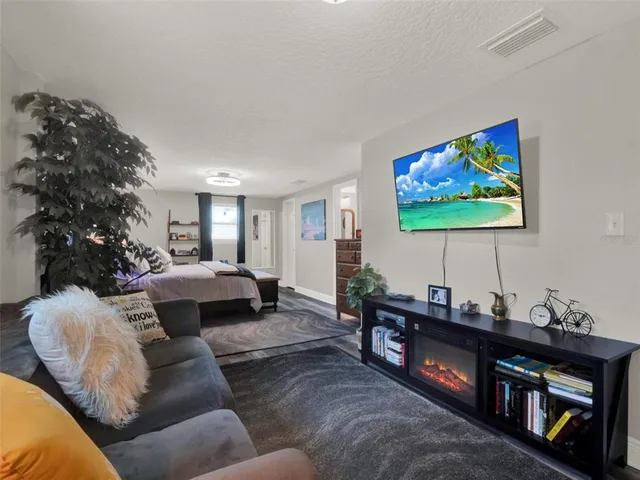 a bedroom with a bed and dresser with wooden floor