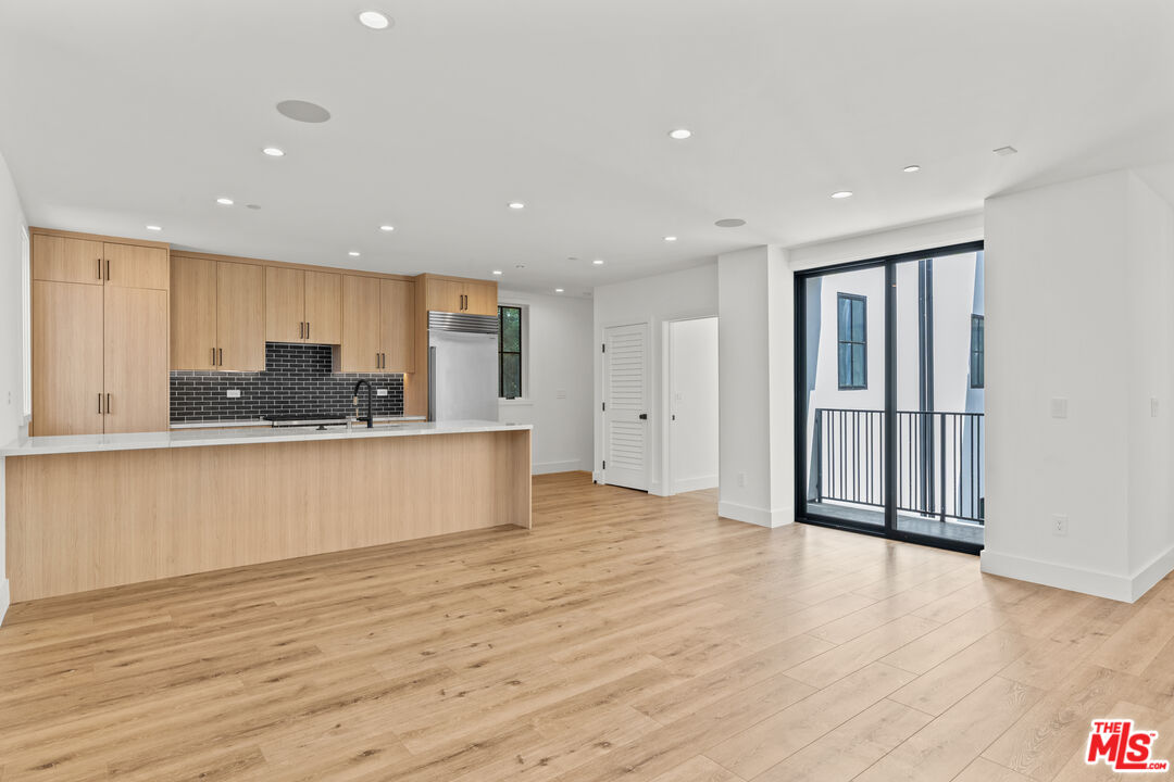 a view of kitchen with kitchen island wooden floor center island stainless steel appliances and cabinets
