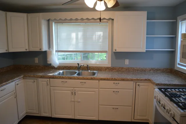 a kitchen with granite countertop a sink window and cabinets