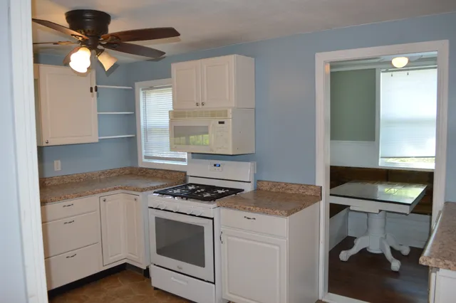 a kitchen with granite countertop cabinets a stove a sink and a potted plant