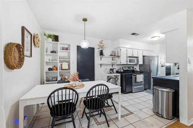 a kitchen with stainless steel appliances a dining table chairs a refrigerator and a stove