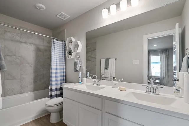 a bathroom with a double vanity sink toilet mirror and shower