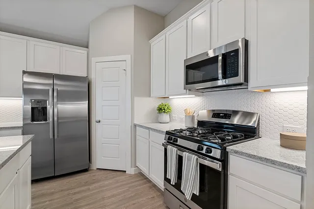 a kitchen with stainless steel appliances white cabinets a stove and microwave