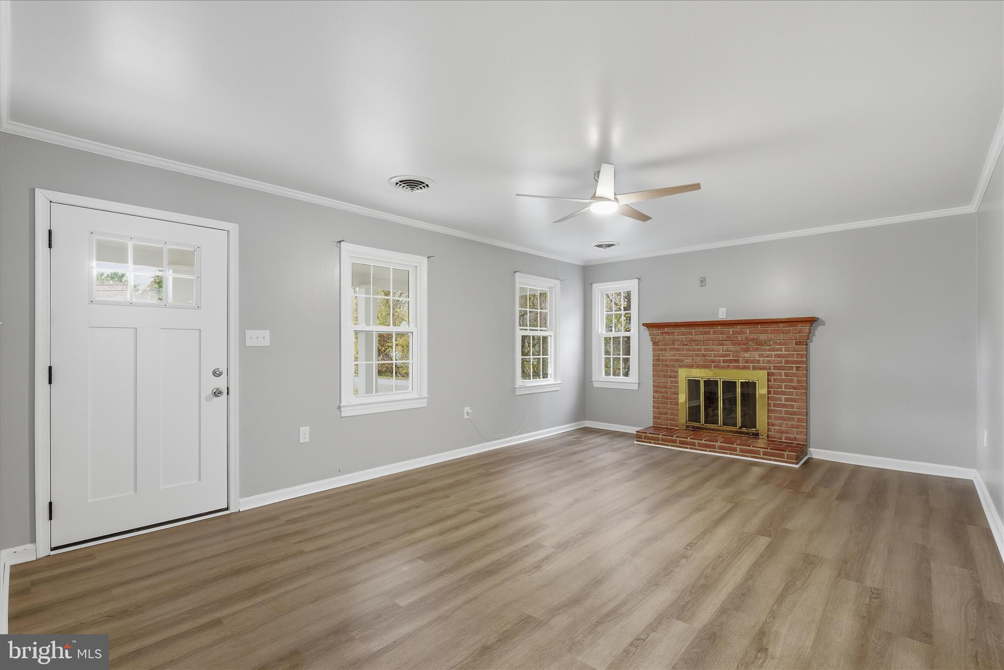 130 Cox Road Huntingtown, MD 20639 - Photo 5 of 41 a view of an empty room with wooden floor fireplace and a window