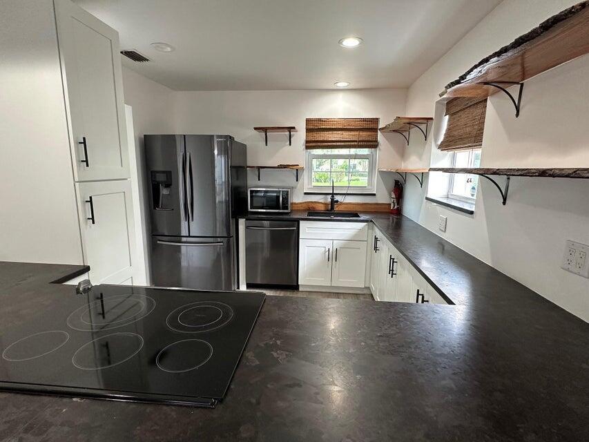 423 Waterside Circle Lake Worth, FL 33462 - Photo 4 of 21 a kitchen with stainless steel appliances granite countertop a refrigerator and a stove top oven