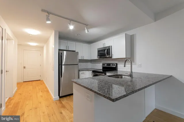 a kitchen with a refrigerator a microwave a sink and cabinets