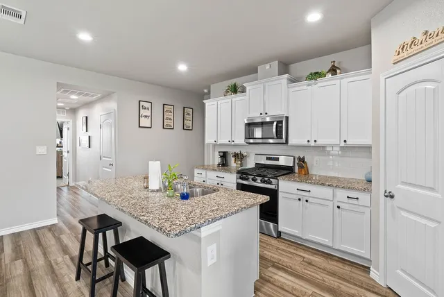 a kitchen with granite countertop white cabinets and refrigerator
